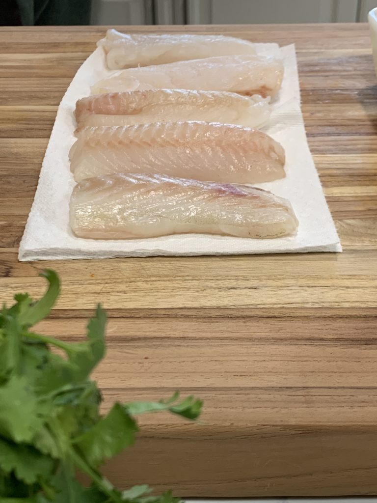 cod fish slices being blotted before dipping into batter